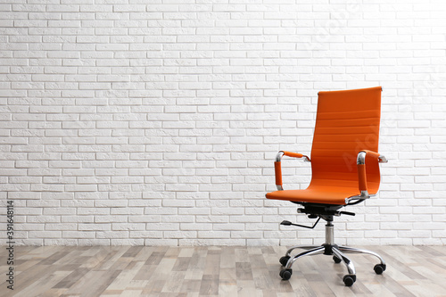 Comfortable office chair near white brick wall indoors. Space for text photo