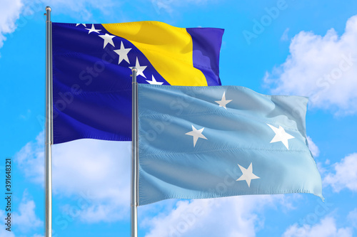 Micronesia and Bosnia Herzegovina national flag waving in the windy deep blue sky. Diplomacy and international relations concept.