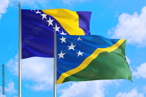 Solomon Islands and Bosnia Herzegovina national flag waving in the windy deep blue sky. Diplomacy and international relations concept.