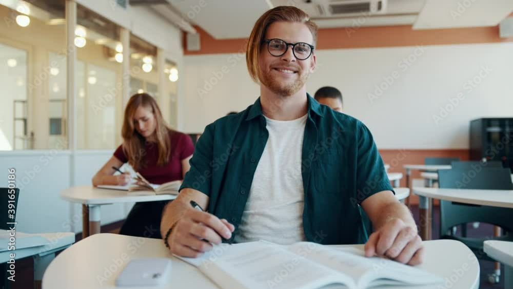 Young man in colleague classroom looking at camera and smiling. Male ...