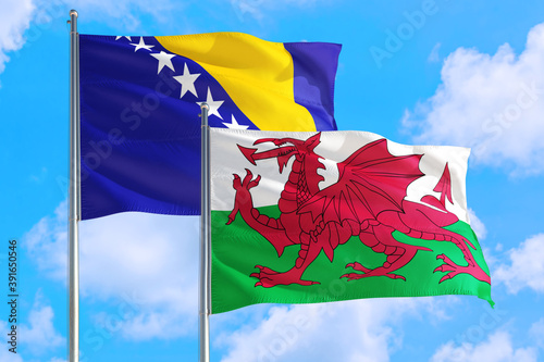 Wales and Bosnia Herzegovina national flag waving in the windy deep blue sky. Diplomacy and international relations concept.
