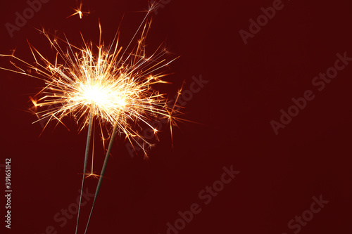 Bright burning sparklers on red background  closeup. Space for text