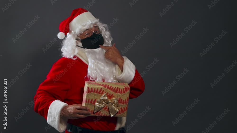 Papa noel con mascarilla pandemia dando regalo mexicano latino