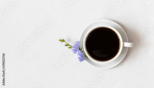 Healthy chicory drink and blue flower on white background. Herbal coffee substitute. Copy space, top view.