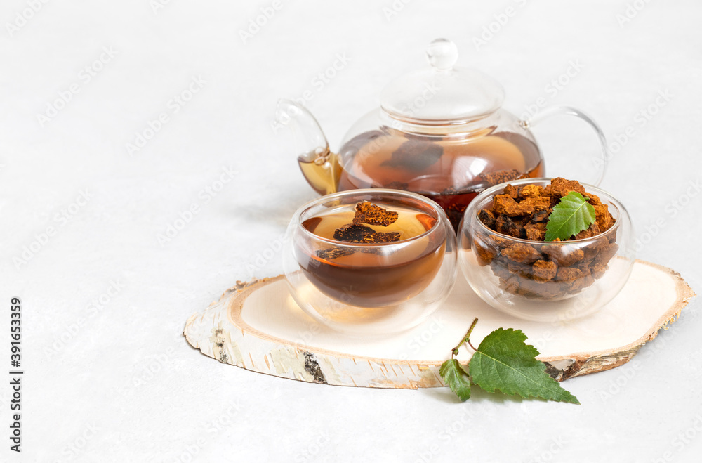 Chaga mushroom drink in glass bowls and teapot on a white background. Healthy infusion with pieces of chaga. Chaga mushroom drink in glass bowls and teapot on a white background. Healthy infusion with pieces of chaga.