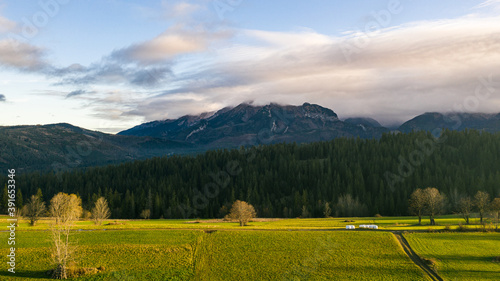 Obraz na płótnie Big blue misty mountain with green and yellow foreground farm fields w salonie
