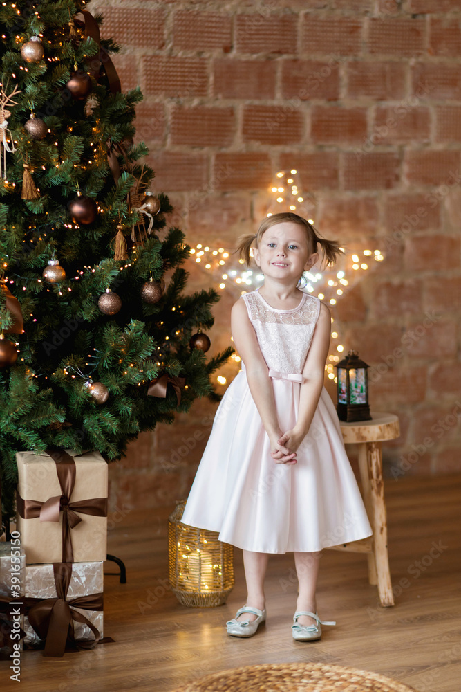 The adorable little girl in gorgeous dress standing near Christmas tree The adorable little girl in gorgeous dress standing near Christmas tree