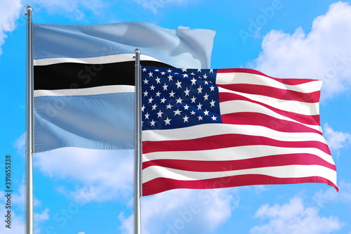 United States and Botswana national flag waving in the windy deep blue sky. Diplomacy and international relations concept.