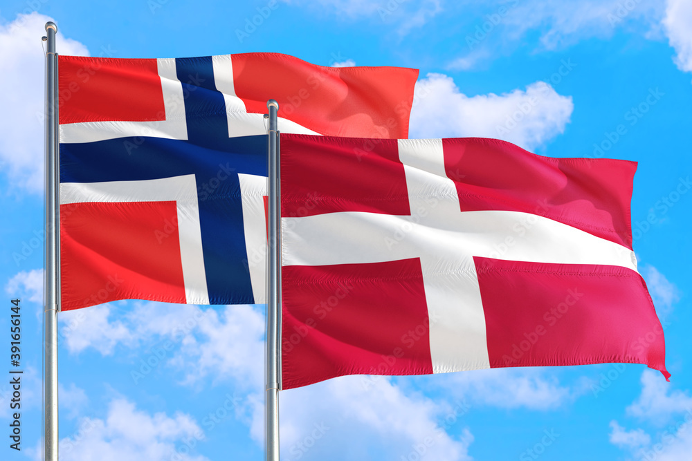 Denmark and Bouvet Islands national flag waving in the windy deep blue sky. Diplomacy and international relations concept. Denmark and Bouvet Islands national flag waving in the windy deep blue sky. Diplomacy and international relations concept.