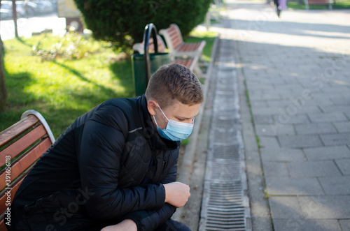 People with face mask. Concept with copy space. Portrait of young man at the street. Photo outdoors in a city. Back to school. School-age boy with a protective medical mask on her on his face.