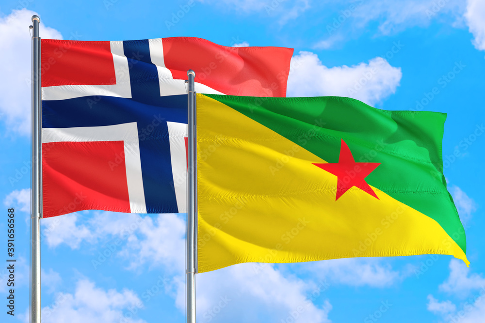 French Guiana and Bouvet Islands national flag waving in the windy deep blue sky. Diplomacy and international relations concept. French Guiana and Bouvet Islands national flag waving in the windy deep blue sky. Diplomacy and international relations concept.