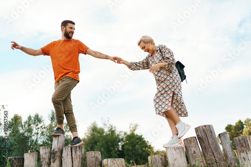Cheerful active coupe walking on stumps on blue sky background