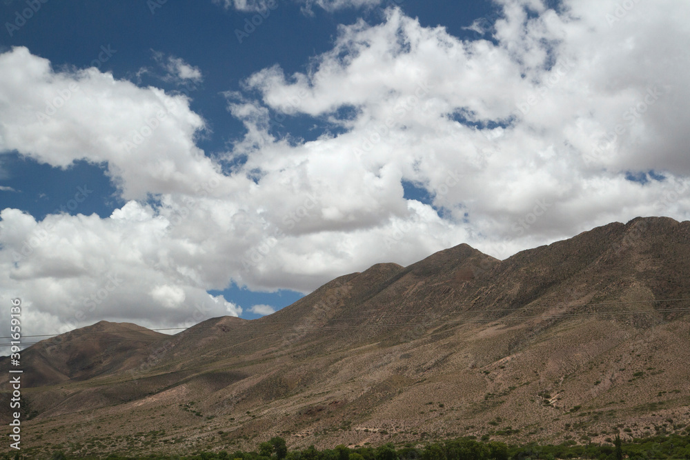 Inspirational landscape. View of the arid mountains under a blue sky with beautiful white clouds, in Jujuy, Argentina. 