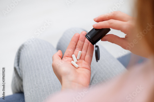 Closeup shot of an unrecognizable woman holding a medication in his hands. Healthcare and medical concept. Female holding three white pills in hand at his home or office. the view from the top