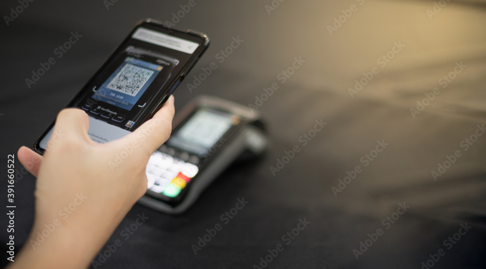 Female hand scanning the QR code with mobile phone for pay at the shop Female hand scanning the QR code with mobile phone for pay at the shop