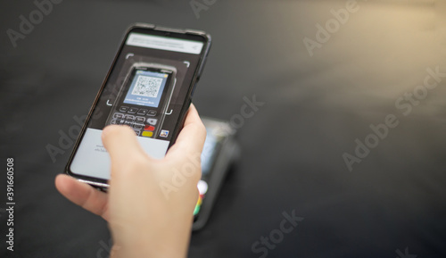 Female hand scanning the QR code with mobile phone for pay at the shop