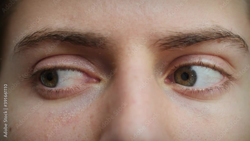 Close up of Man's face. Attractive boy looking around with beautiful blue eyes. Caucasian young male model with blue, green, grey eyes. Slow-motion, macro extreme close-up, 4K.