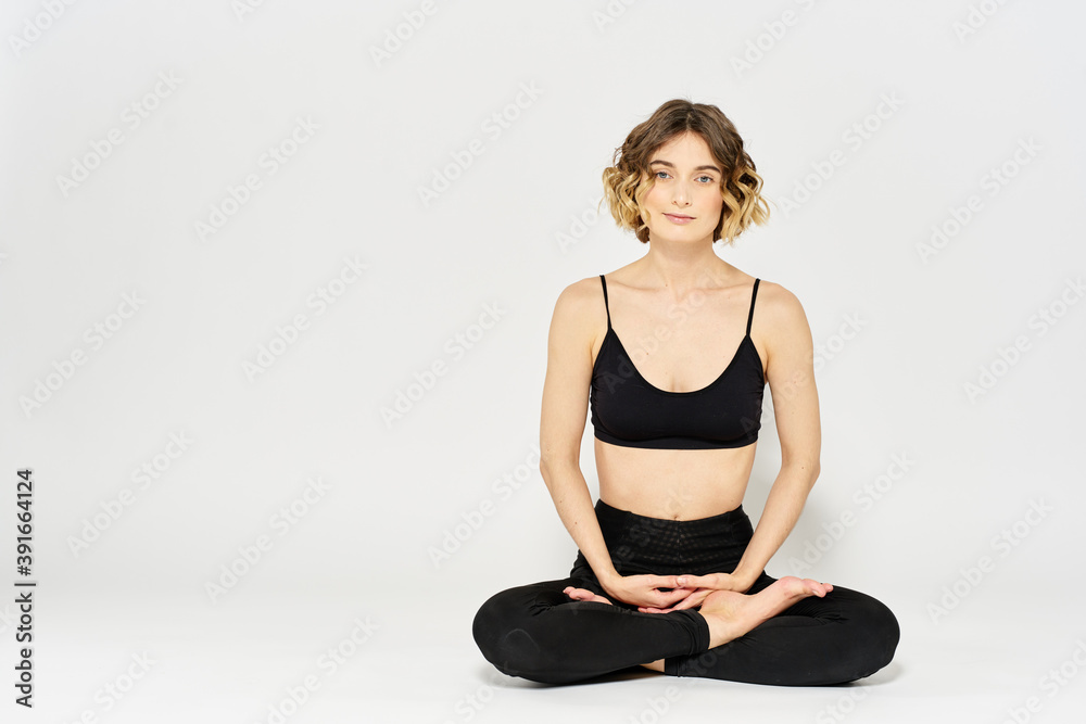 Woman in leggings meditate in a light room with her legs crossed yoga asana Woman in leggings meditate in a light room with her legs crossed yoga asana