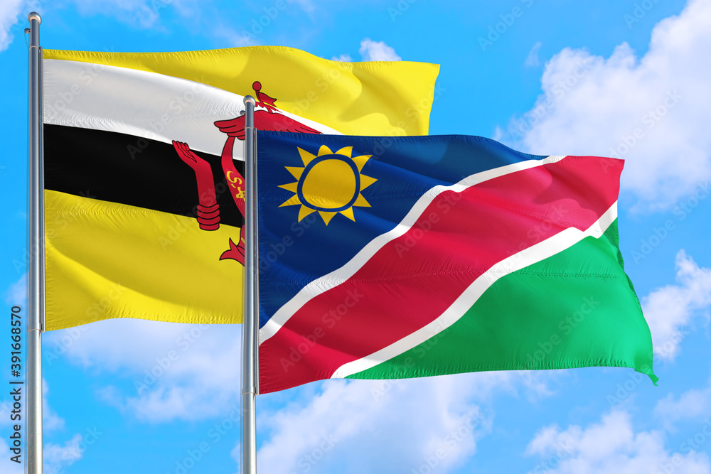 Namibia and Brunei national flag waving in the windy deep blue sky. Diplomacy and international relations concept. Namibia and Brunei national flag waving in the windy deep blue sky. Diplomacy and international relations concept.