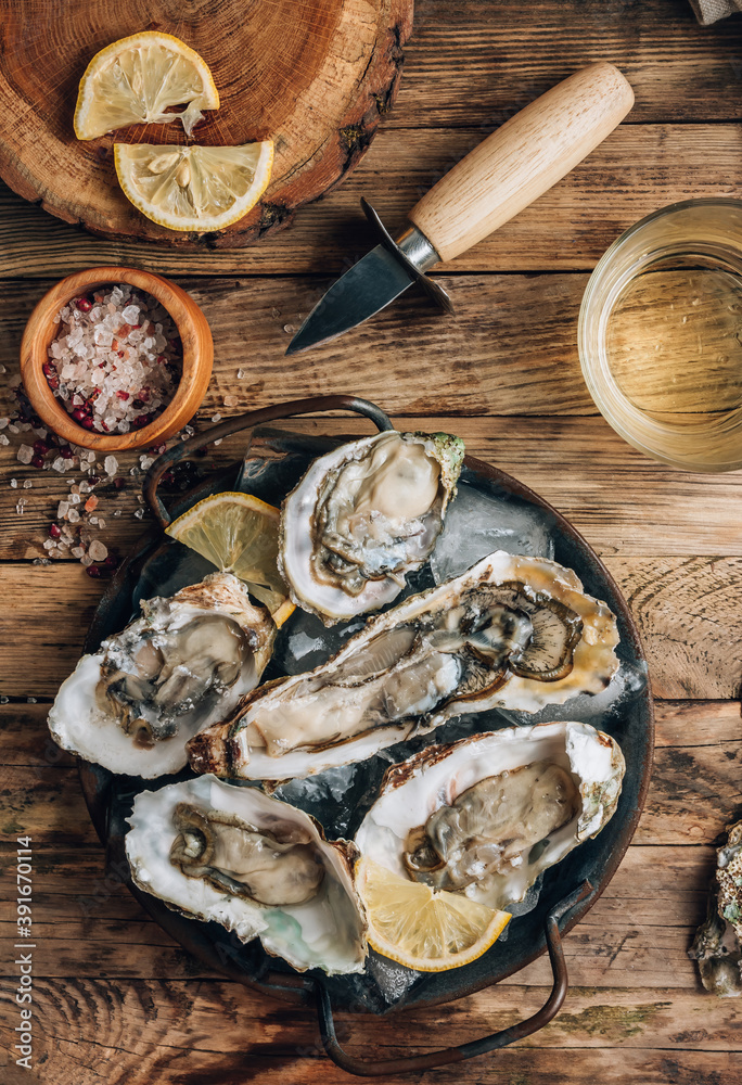 Fresh oysters with ice and lemon on a rustic wooden background. Fresh oysters with ice and lemon on a rustic wooden background.