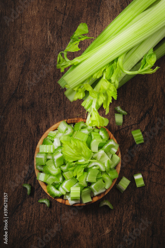 Green celery chopped pieces in bowl, wooden table, top view, copy space photo