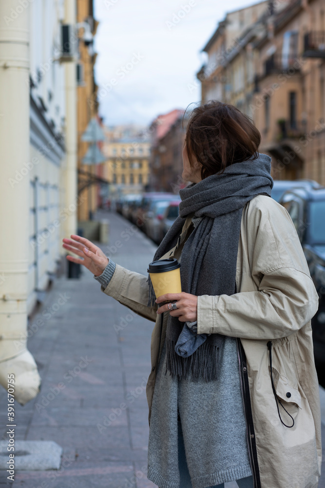 A girl guide in a warm scarf holds coffee and talks about St. Petersburg