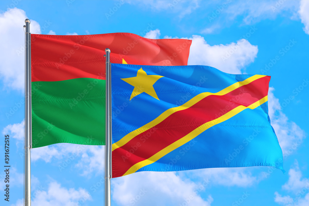 Congo and Burkina Faso national flag waving in the windy deep blue sky. Diplomacy and international relations concept. Congo and Burkina Faso national flag waving in the windy deep blue sky. Diplomacy and international relations concept.
