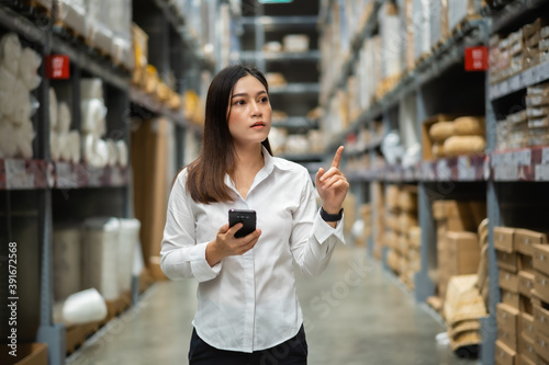 woman worker using smartphone to checking inventory in warehouse store