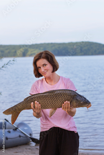 girl fisherman holding white fish, carp