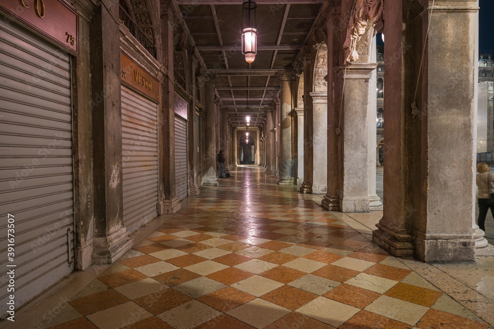 Empty arcades corridor of St. Mark's Square in Venice, Italy at night