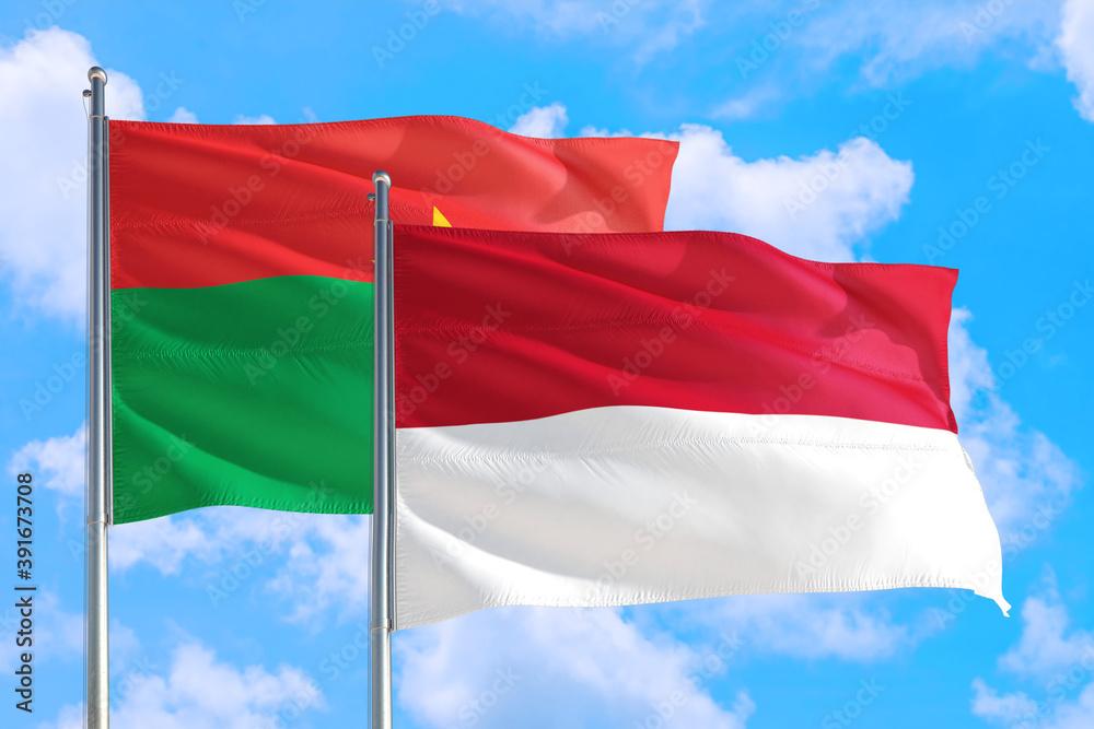 Monaco and Burkina Faso national flag waving in the windy deep blue sky. Diplomacy and international relations concept. Monaco and Burkina Faso national flag waving in the windy deep blue sky. Diplomacy and international relations concept.