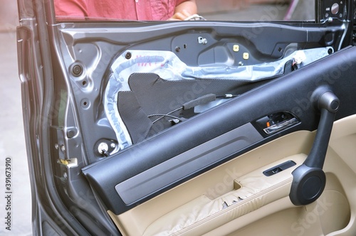 Fixing door's car engine in automobile repair garage. Mechanics in uniform are repairing car while working in auto service