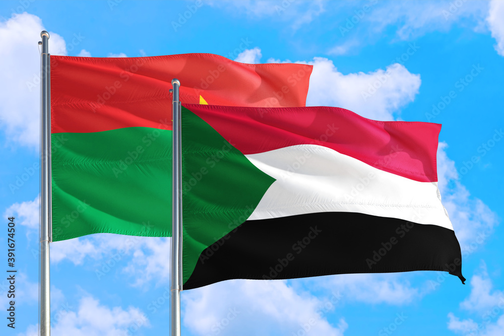 Sudan and Burkina Faso national flag waving in the windy deep blue sky. Diplomacy and international relations concept. Sudan and Burkina Faso national flag waving in the windy deep blue sky. Diplomacy and international relations concept.