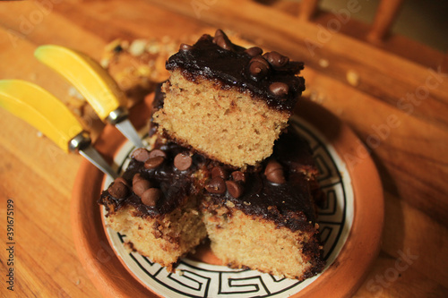 Rustic brazilian banana cake cut in slices with chocolate topping.