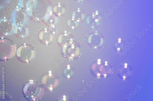 Beatiful shiny clear soap bubbles floating on purple texture background.