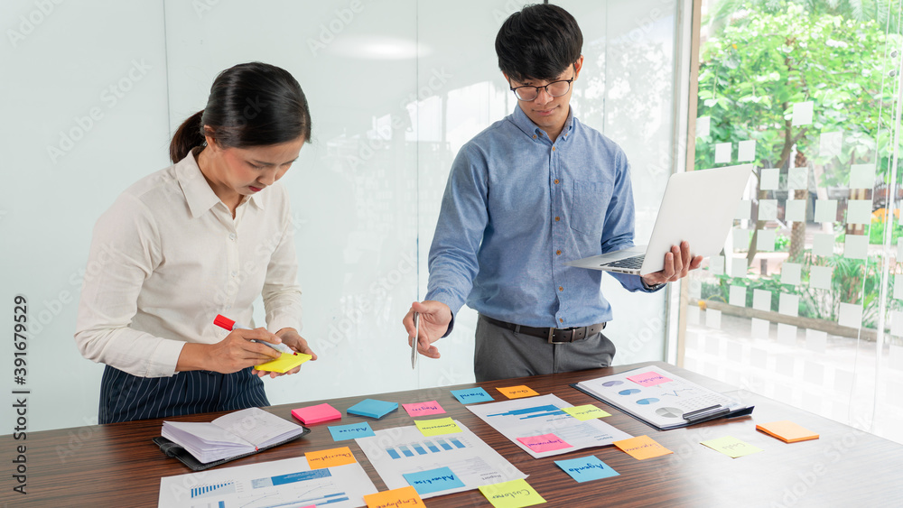 Fototapeta premium Businessman stick colorful notes to brainstorming on the table working on new project to share idea to thinking how to planning new case