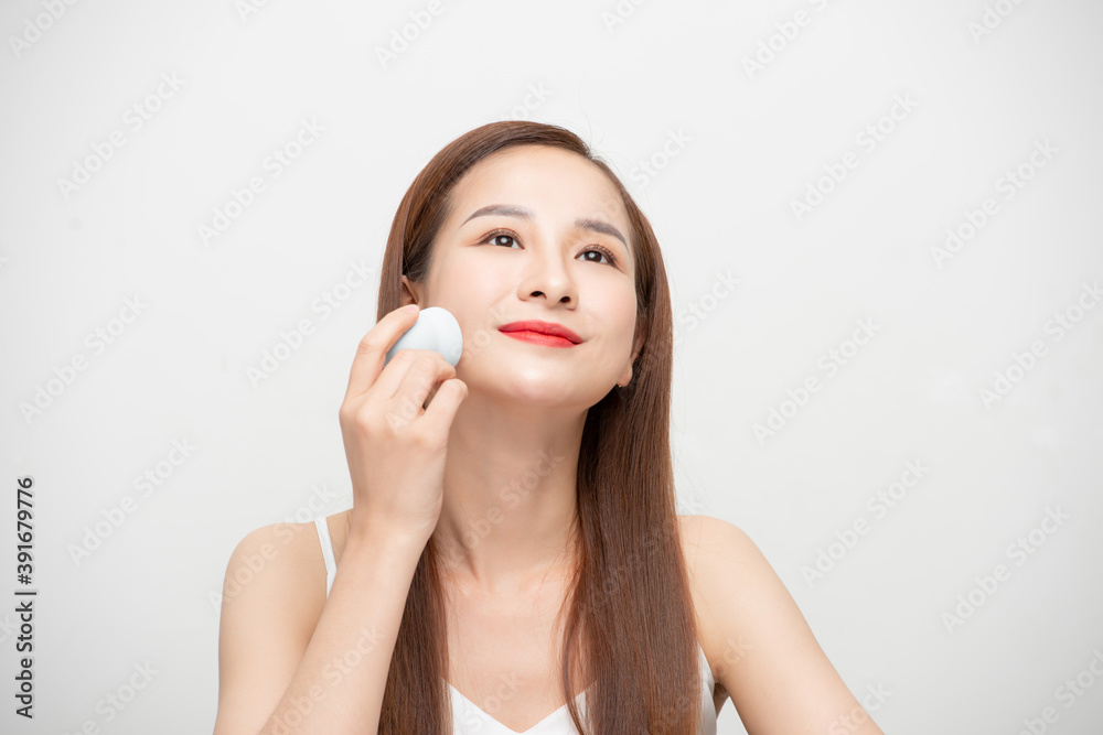 Beauty portrait of a lovely young woman isolated over white background, using makeup sponge Beauty portrait of a lovely young woman isolated over white background, using makeup sponge