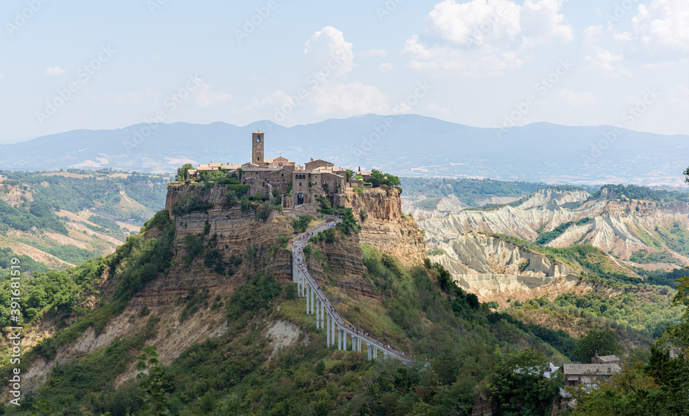 Cività di Bagnoregio sitting on a limestone cliff and slowly decaying. A medieval town center with a church and old houses holds on the plateau among a scenic eroded landscape