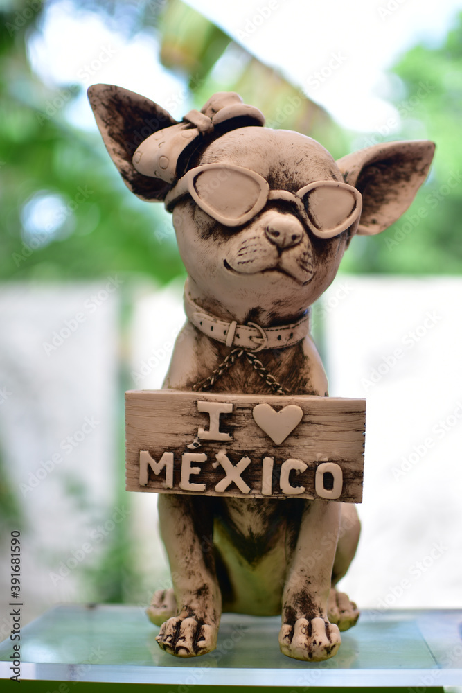 Vertical shot of a cute chihuahua statue with sunglasses and an "I love  Mexico" sign in a garden Photos | Adobe Stock