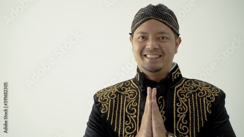 A portrait of a costume traditional Javanese man greeting gesture photo