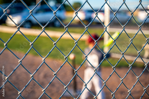 selective focus on chain link fence behind tee ball batter
