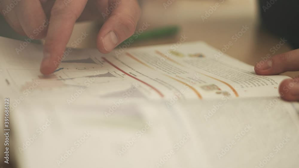 Open page of a statistics text book with graphs and a finger pointing at different parts. Close up. racking Focus. Open page of a statistics text book with graphs and a finger pointing at different parts. Close up. racking Focus.