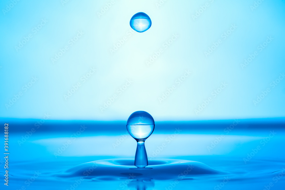 Water drop splashing into blue water surface Water drop splashing into blue water surface