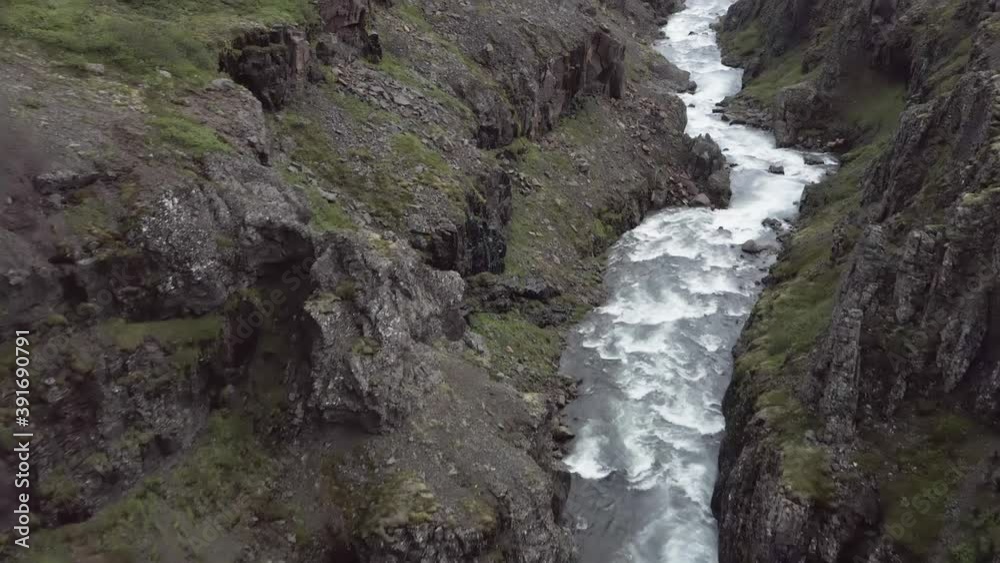 Aerial flying through wild valley with whitewater rapids and rocky cliffs