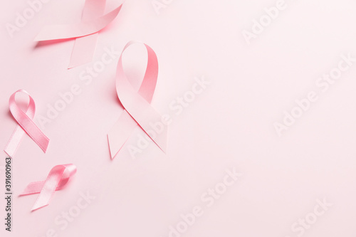 Pink ribbons on color background. Breast cancer awareness concept © Pixel-Shot