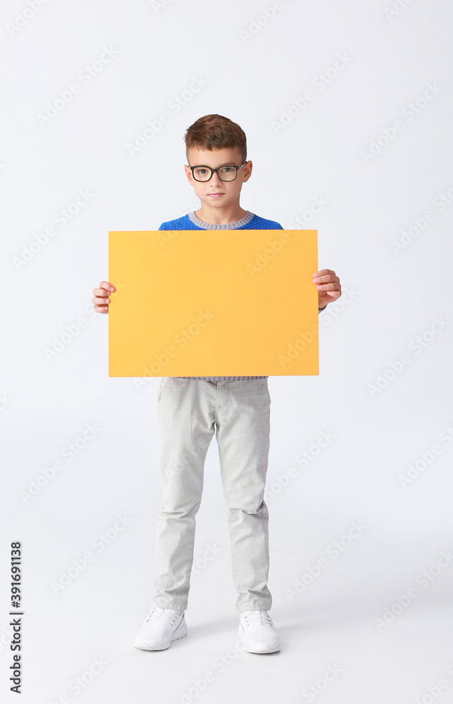 Little boy with blank paper sheet on light background Little boy with blank paper sheet on light background
