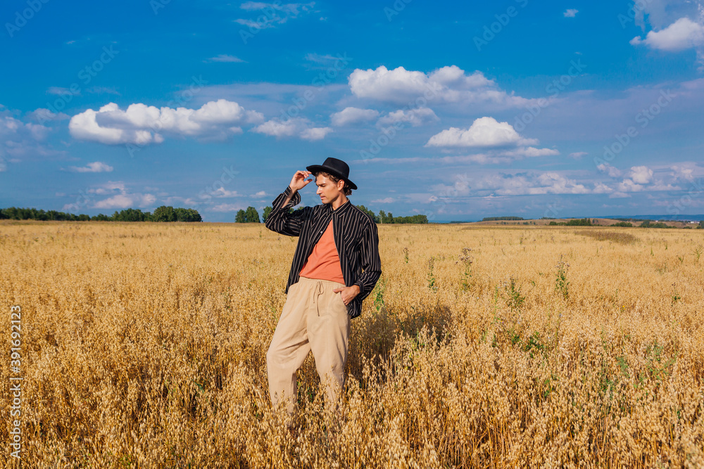 Tall handsome man with black hat standing at golden oat field. Tall handsome man with black hat standing at golden oat field.
