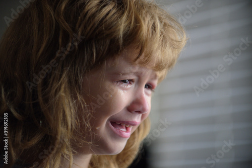 Close up face of little boy crying with tears. Portrait of a kid Cry at home. Child sad Emotions.