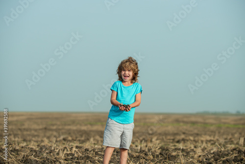 Cute little kid farmer working on field. Soil planting and seeding concept. © Volodymyr