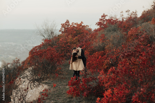 Romantic sensual couple hugging on the rocky hill. Man passionately kissing his girlfriend on the neck.